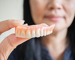 a patient smiling and holding their denture