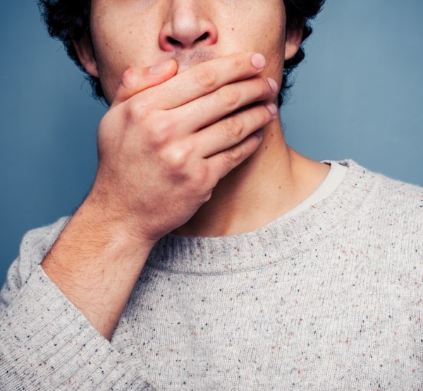 Man in need of emergency dentistry covering his mouth