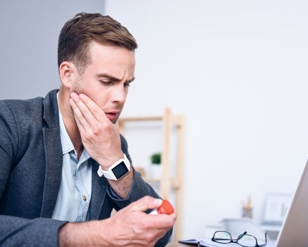 Man in need of emergency dentistry holding jaw in pain