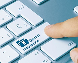 Patient pressing dental insurance button on keyboard