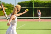 Friends playing tennis on sunny day