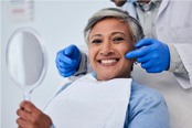 Woman smiling while holding handheld mirror