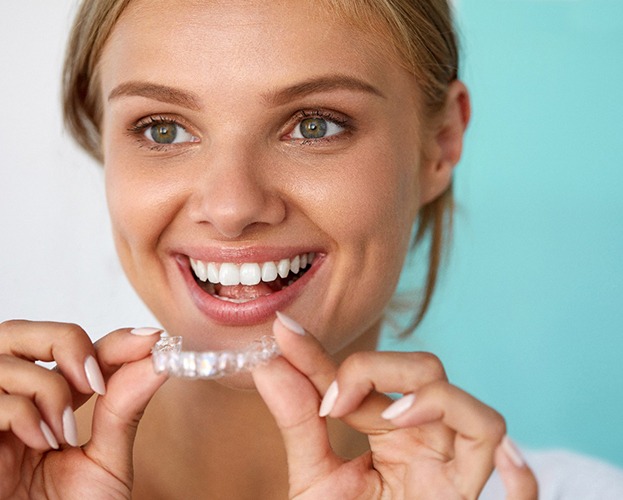 Smiling woman using take-home teeth whitening in Dudley