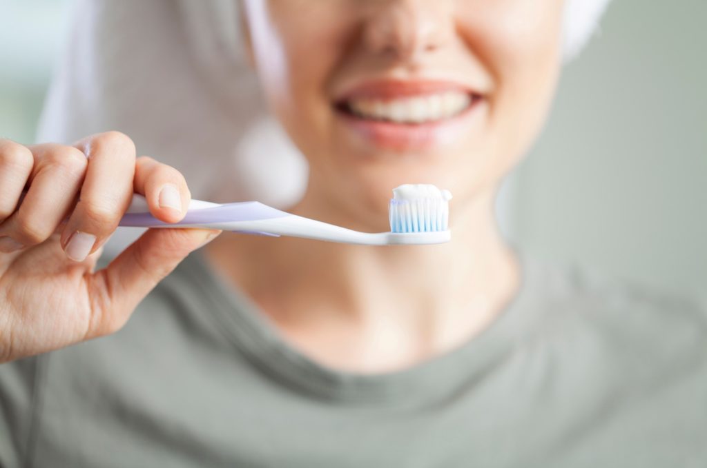 Woman smiling while brushing her teeth