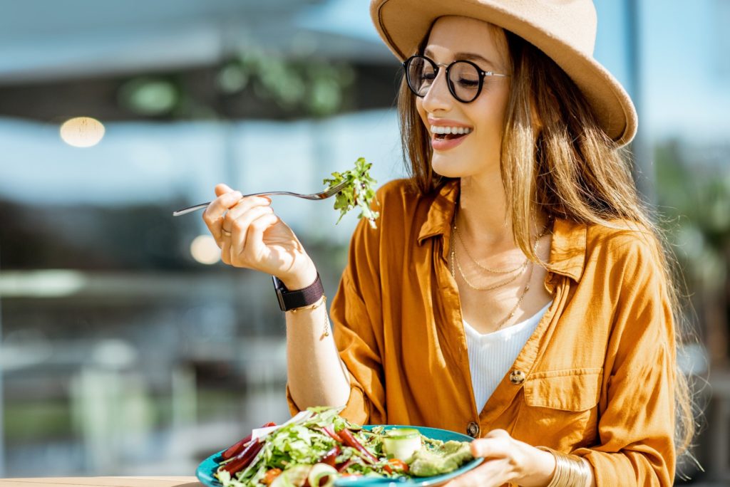 Woman with veneers smiling while eating a salad