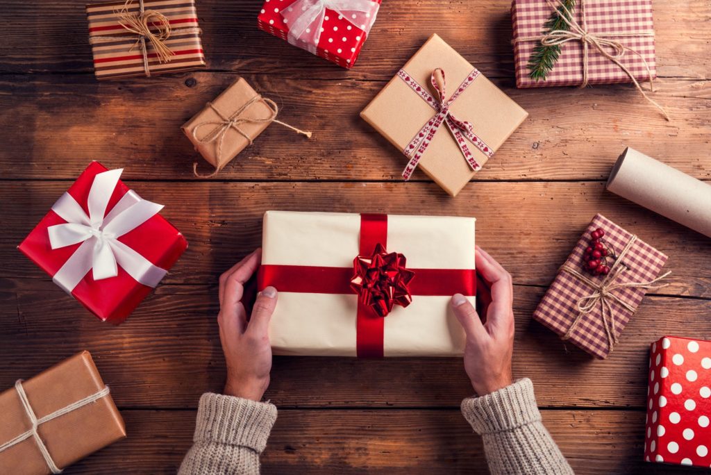 Person in cream sweater wrapping holiday gifts