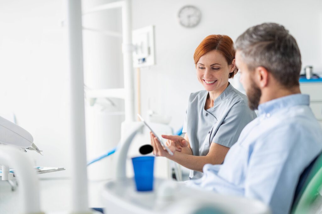 Smiling dental assistant showing patient image on tablet